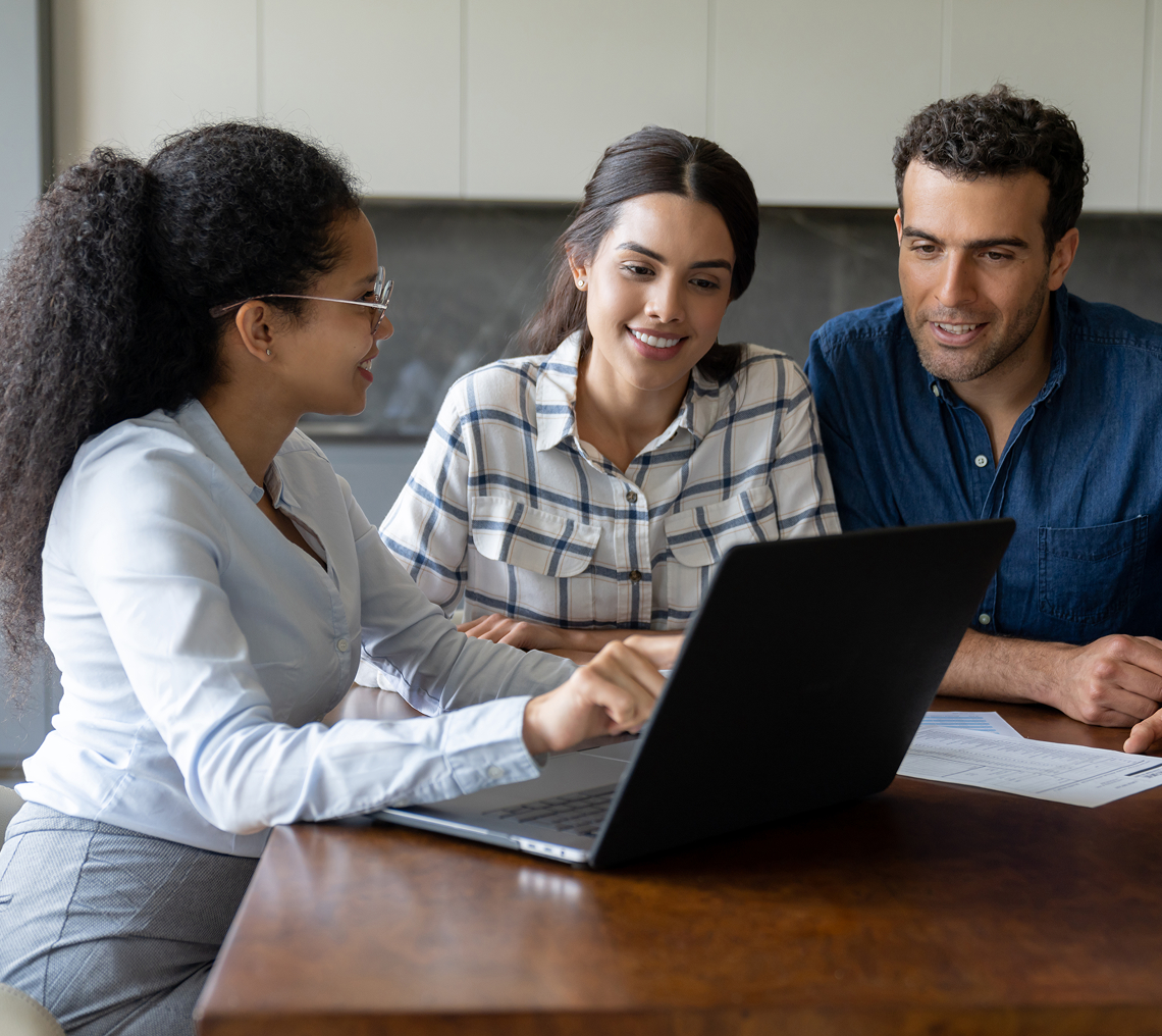 Three people discussing over a laptop.