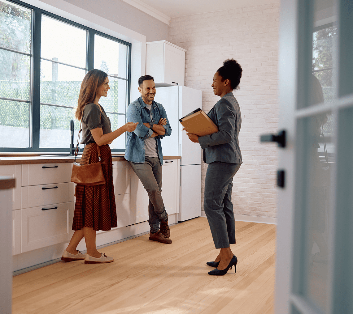 Real estate agent showing couple a kitchen.